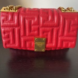 Balmain 1945 red quilted lambskin bag with gold accents.